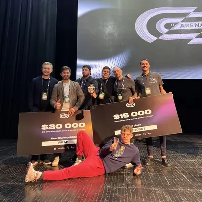 Sasha Voloshyn with the WRAP and 3rd-place teams on the Lviv IT Arena 2022 stage, holding $20,000 and $15,000 cheques